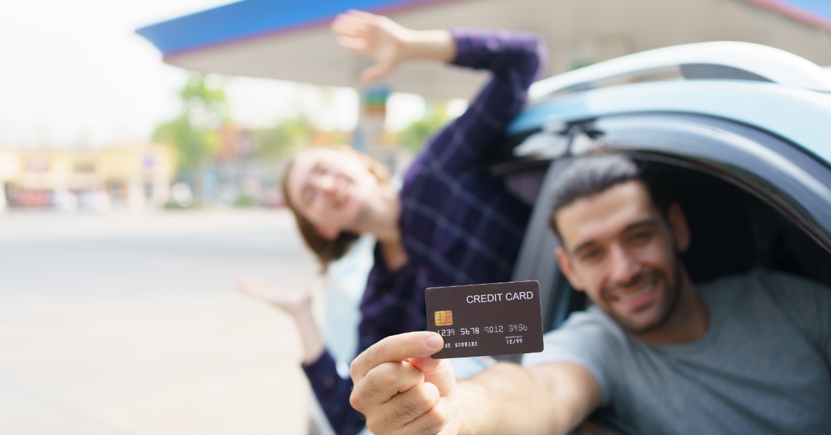 happy couple showing card in car