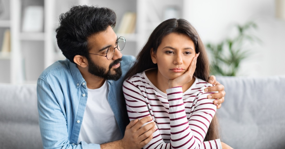 husband comforting upset wife on couch
