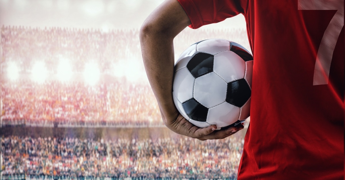 male footballer holding ball in stadium