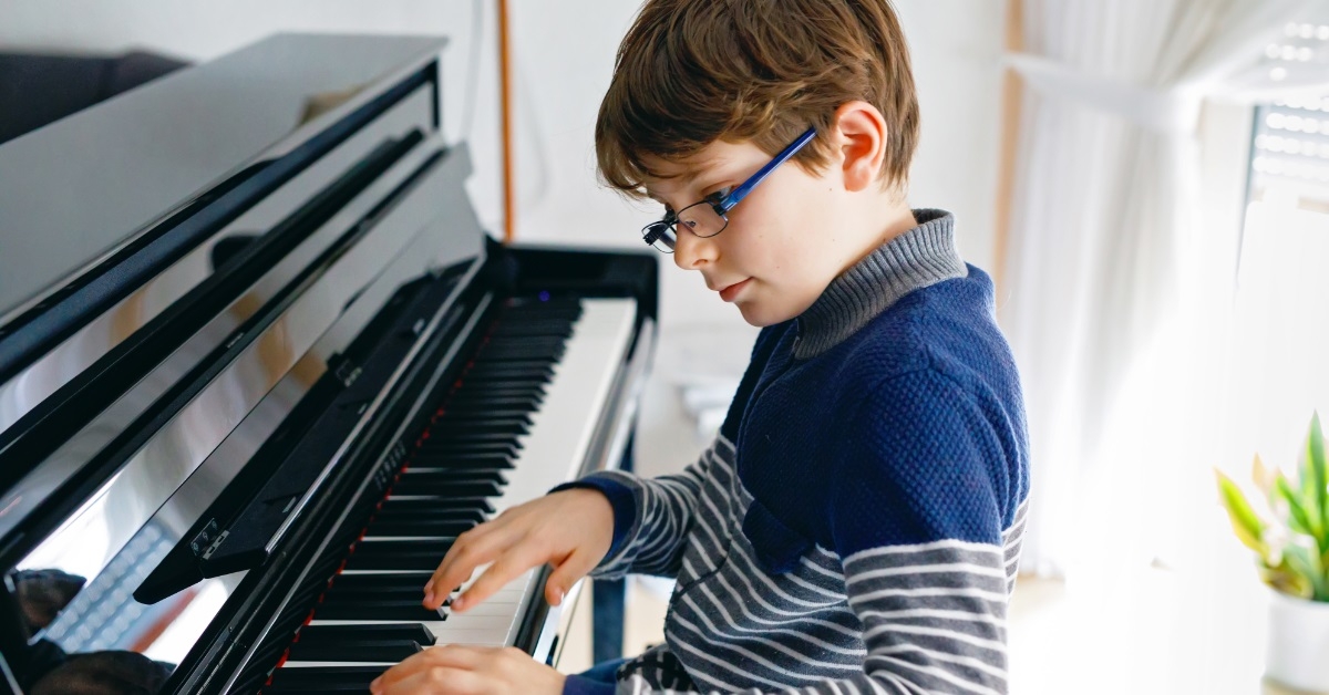 boy wearing glasses playing piano