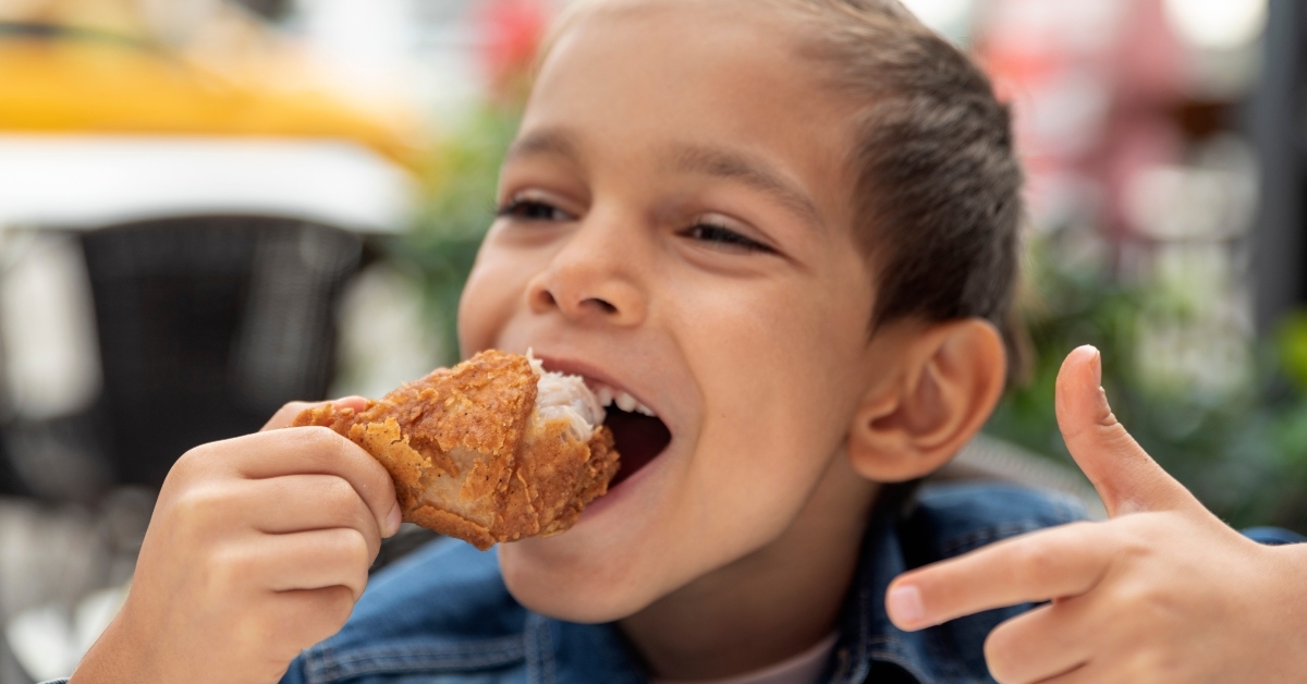 little boy eats fried chicken