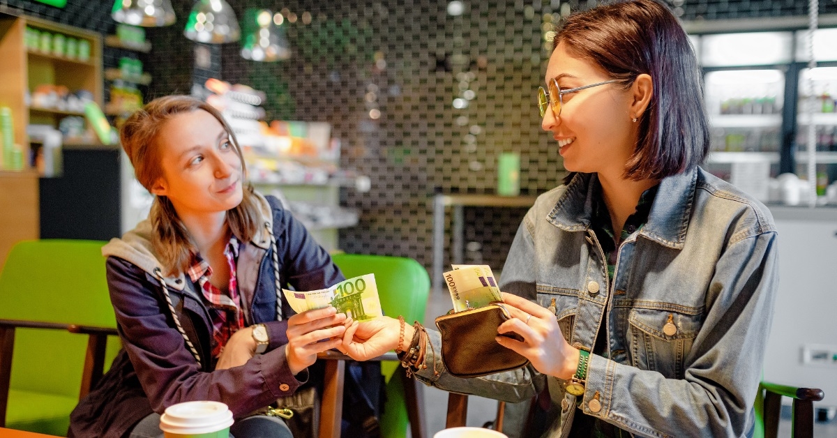 female friends giving money to friend
