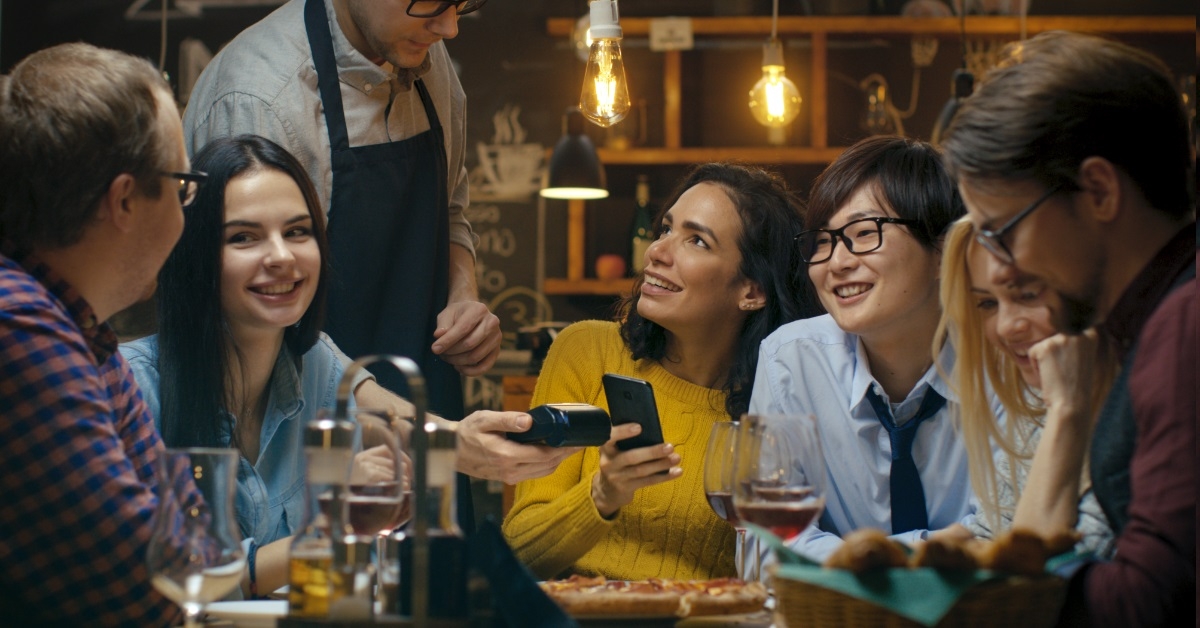 woman paying using mobile at bar