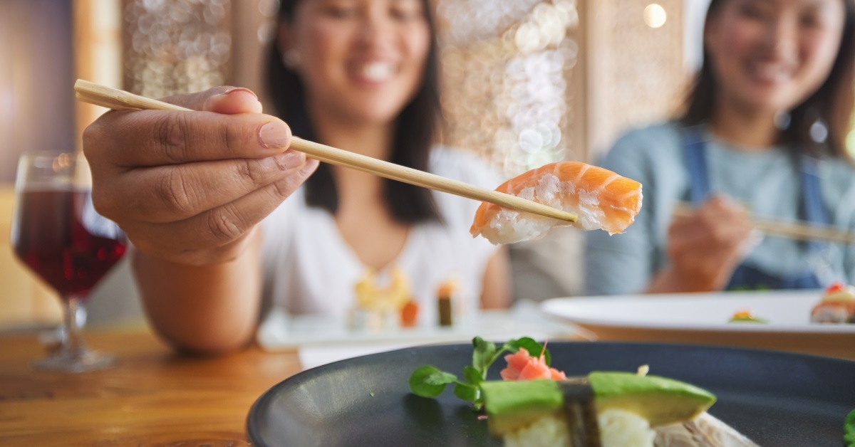women eating sushi using chopstick