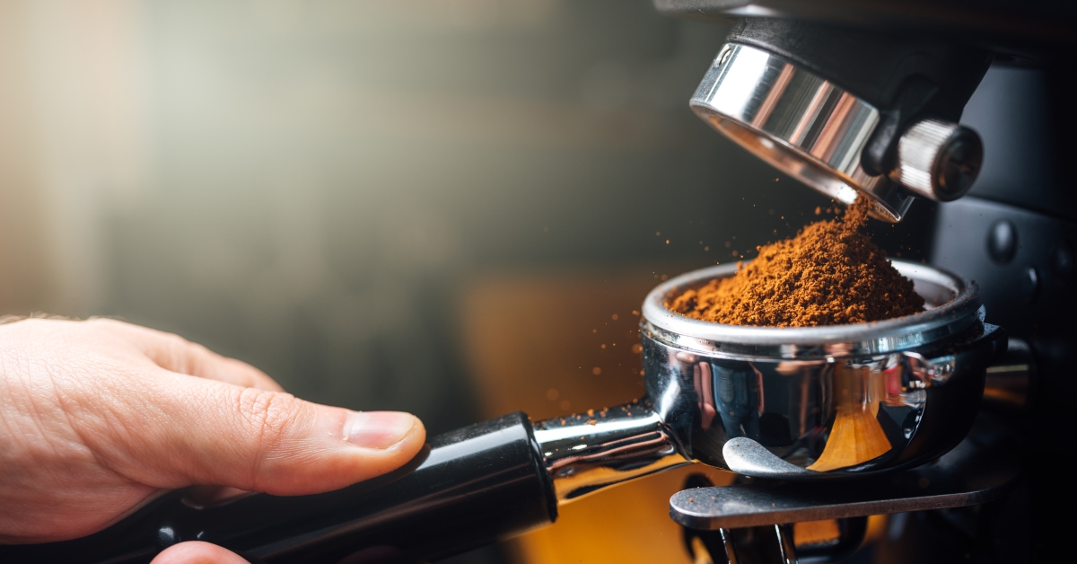 ground coffee pouring into a portafilter with a grinder