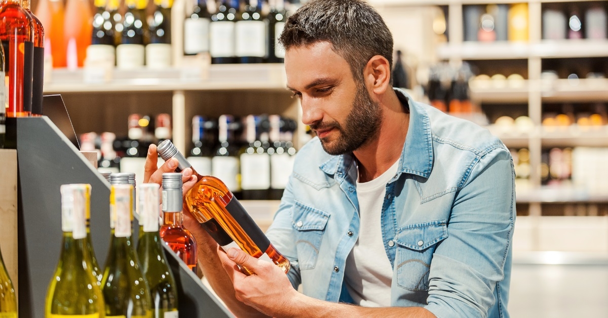 man choosing wine bottle at store