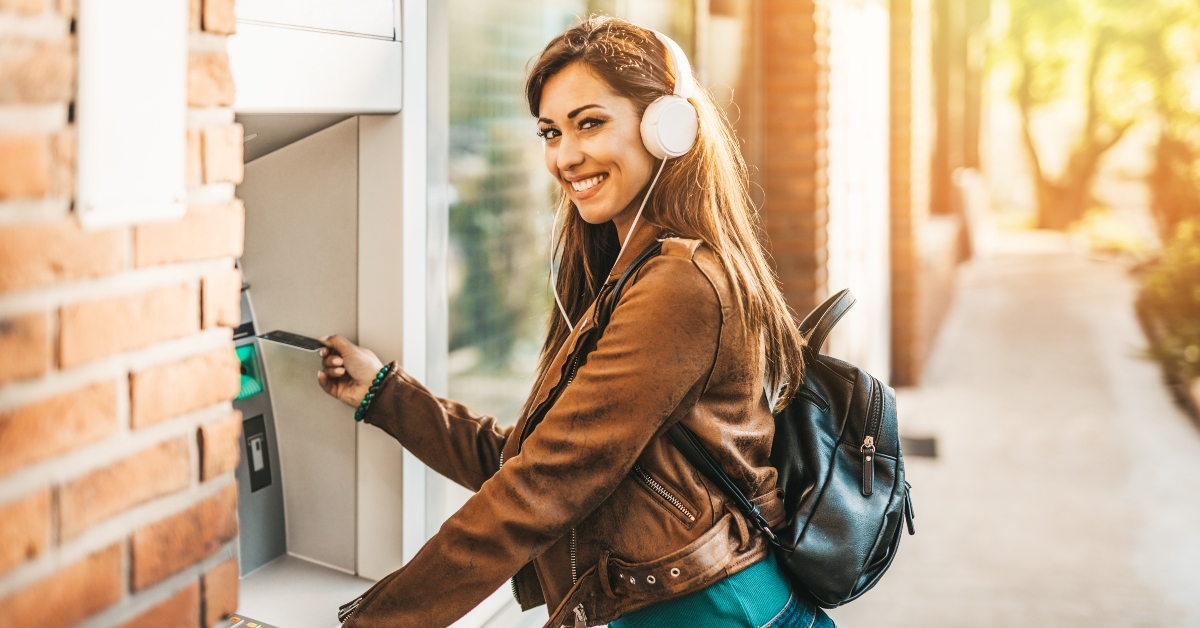 Woman wearing headphones and using an ATM