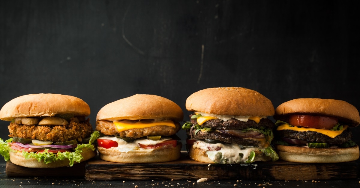 Assorted delicious burgers on dark table
