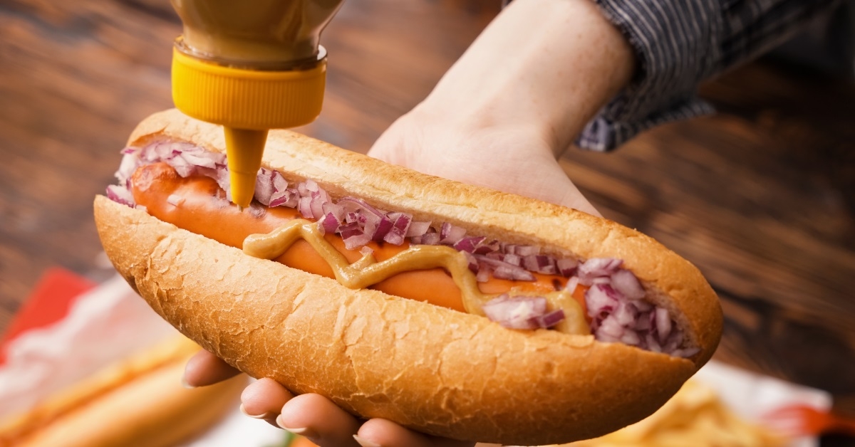 Woman squeezing sauce on hot dog