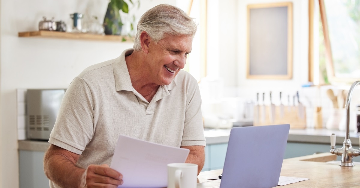 happy senior male investor using laptop