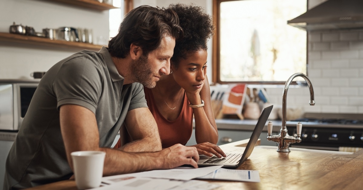 couple reading bills using laptop