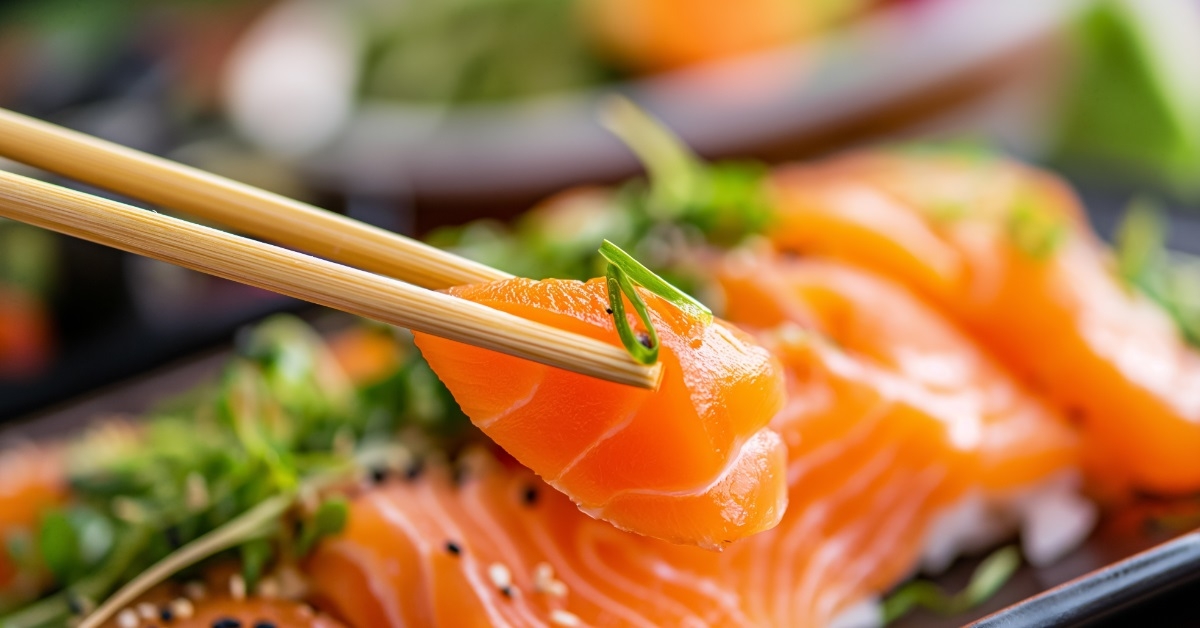 chopsticks holding salmon sashimi