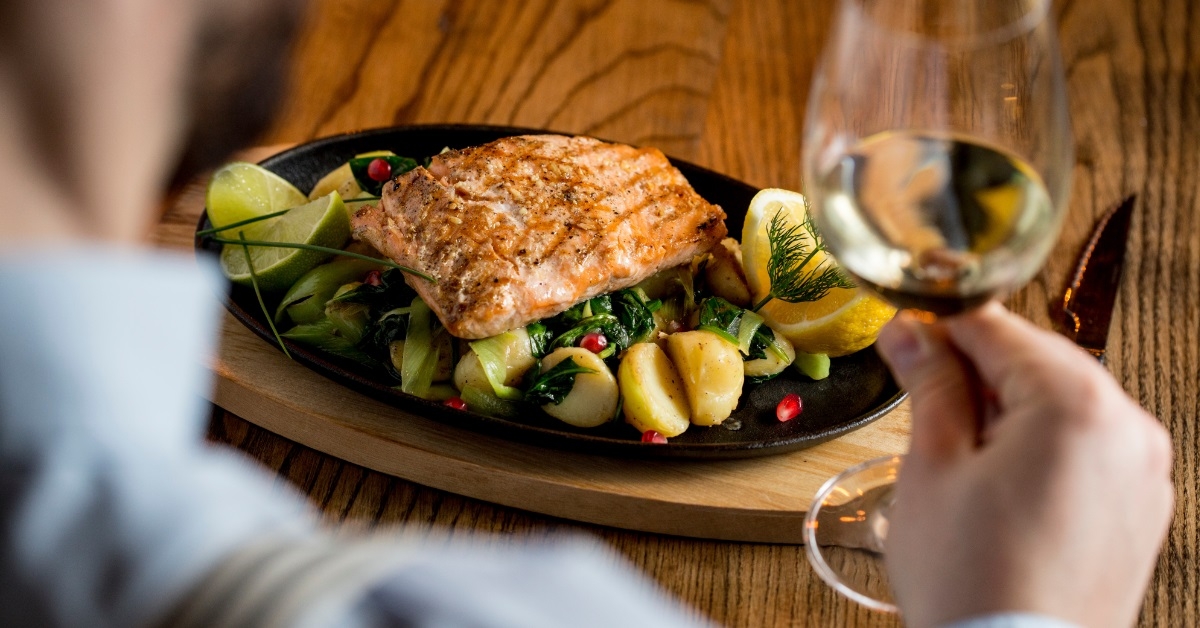 man eating salmon fillet with champagne