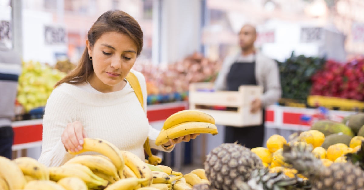 woman picks ripe bananas at grocery supermarket