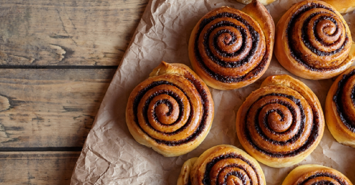 Cinnamon rolls buns on a wooden breakfast table and parchment paper. 