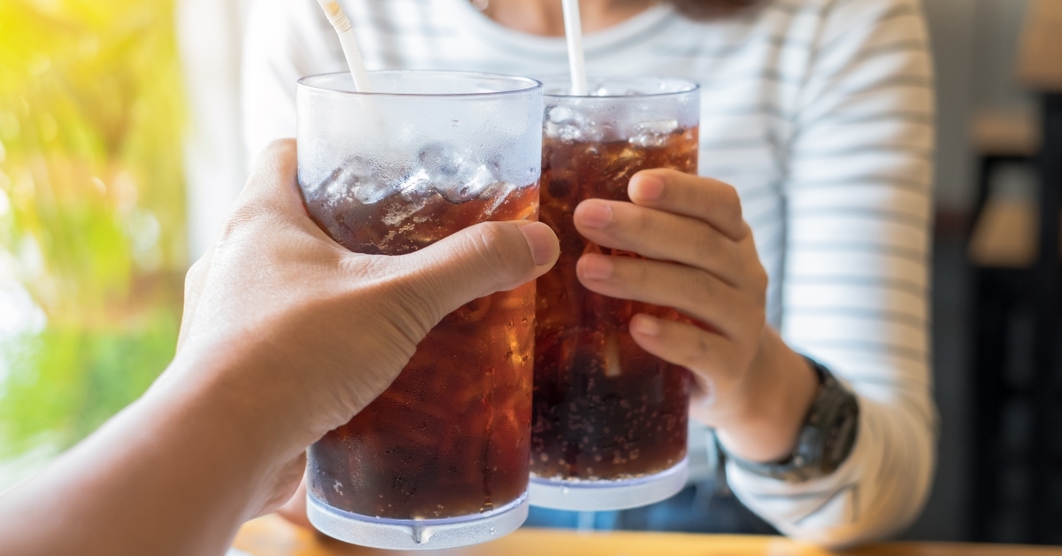 hands holding glasses of cola