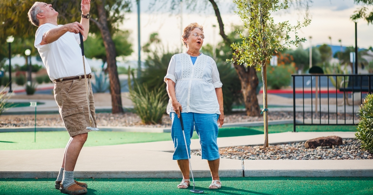 retired couple having fun playing mini golf