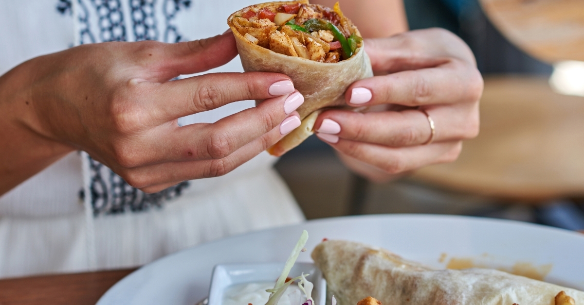 Female hands holding tasty mexican burrito