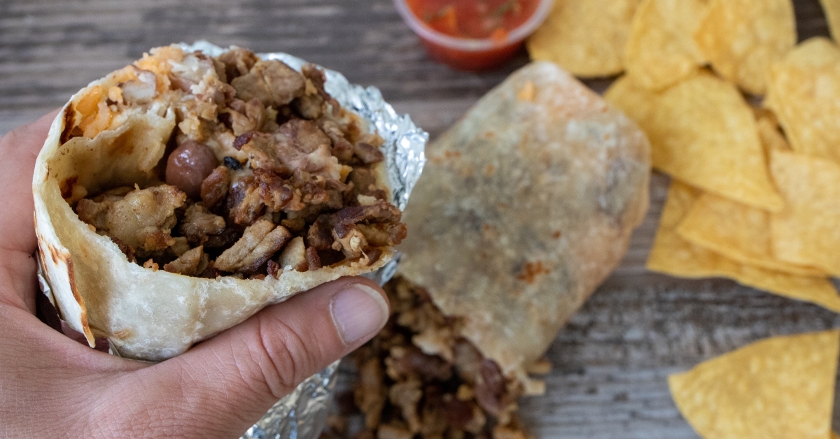 Hand holding carne asada beef burrito