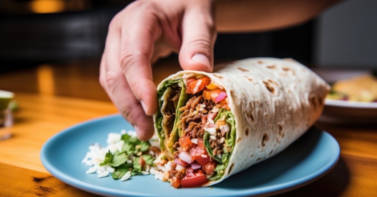hand placing half burrito on plate