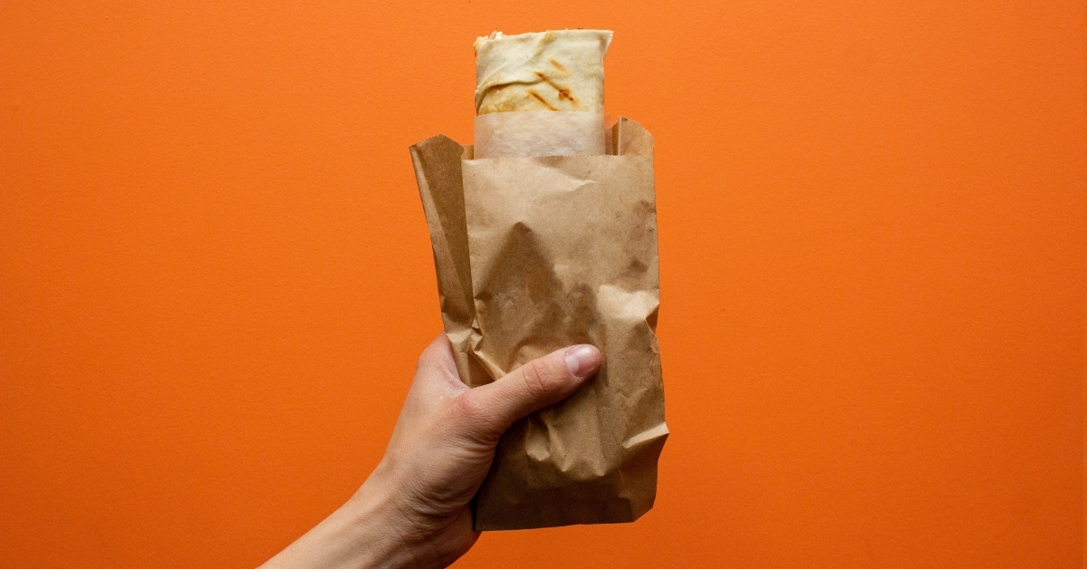 shawarma in hand on orange background