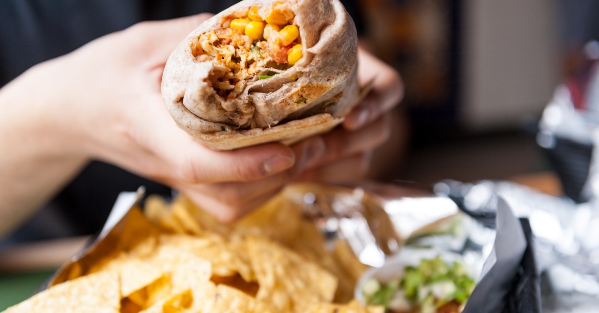 woman handling huge burrito at restaurant