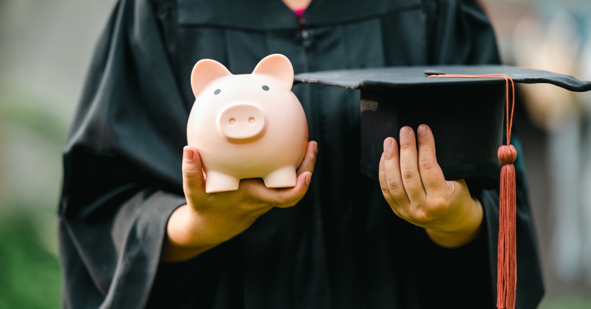 graduate holding piggy bank