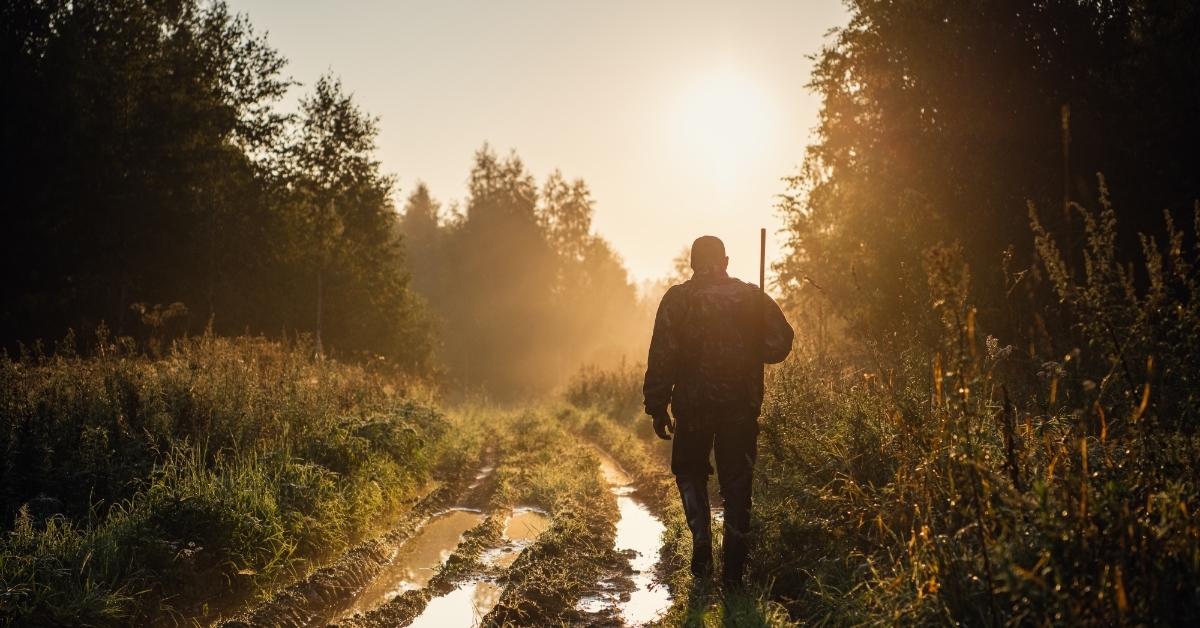 hunter with shotgun walking through trail
