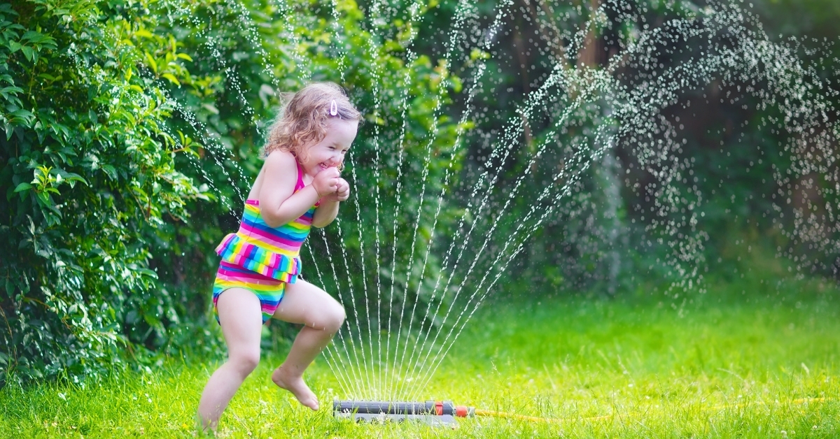 Little girl playing with garden sprinkle