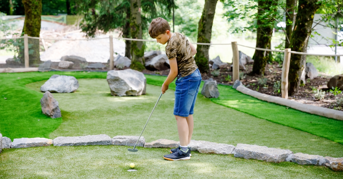 school kid playing mini golf