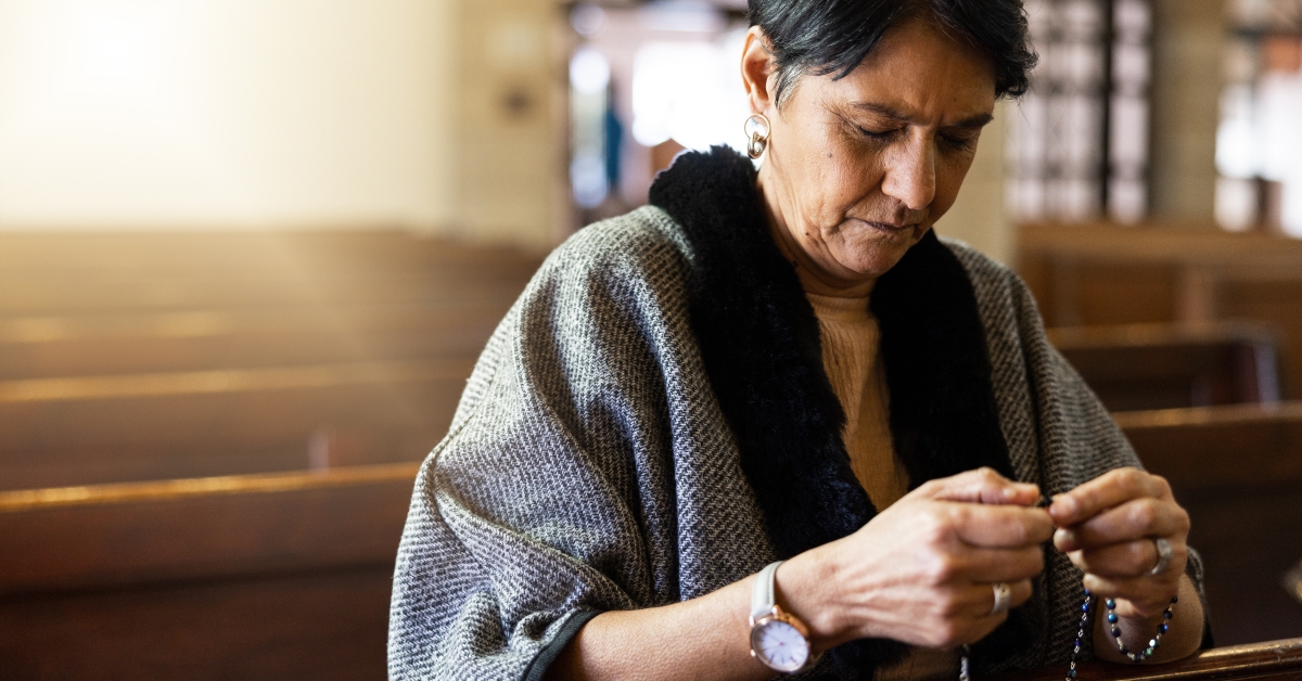 senior woman praying with rosary