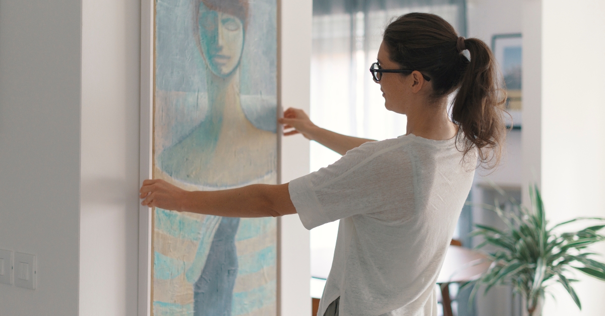 woman hanging a painting