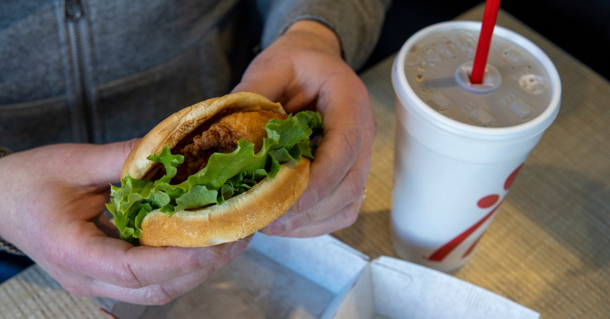 mans hands holding chicken burger