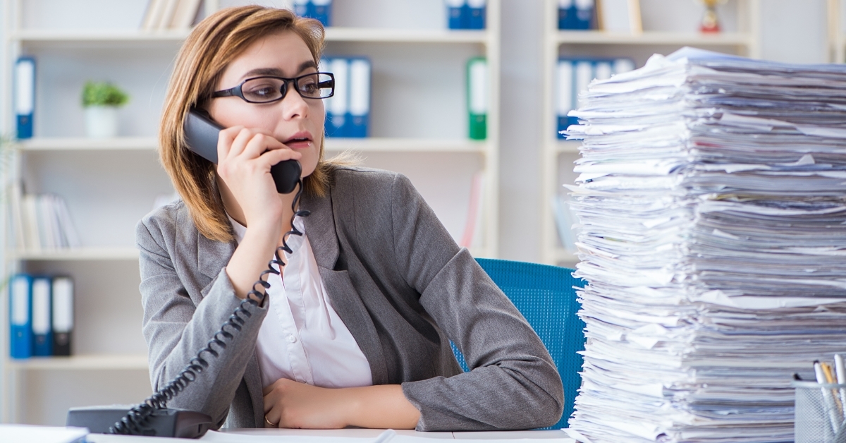 stressed business woman besides pile of papers