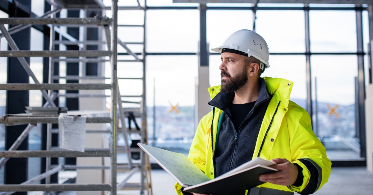 male engineer holding blueprints on site