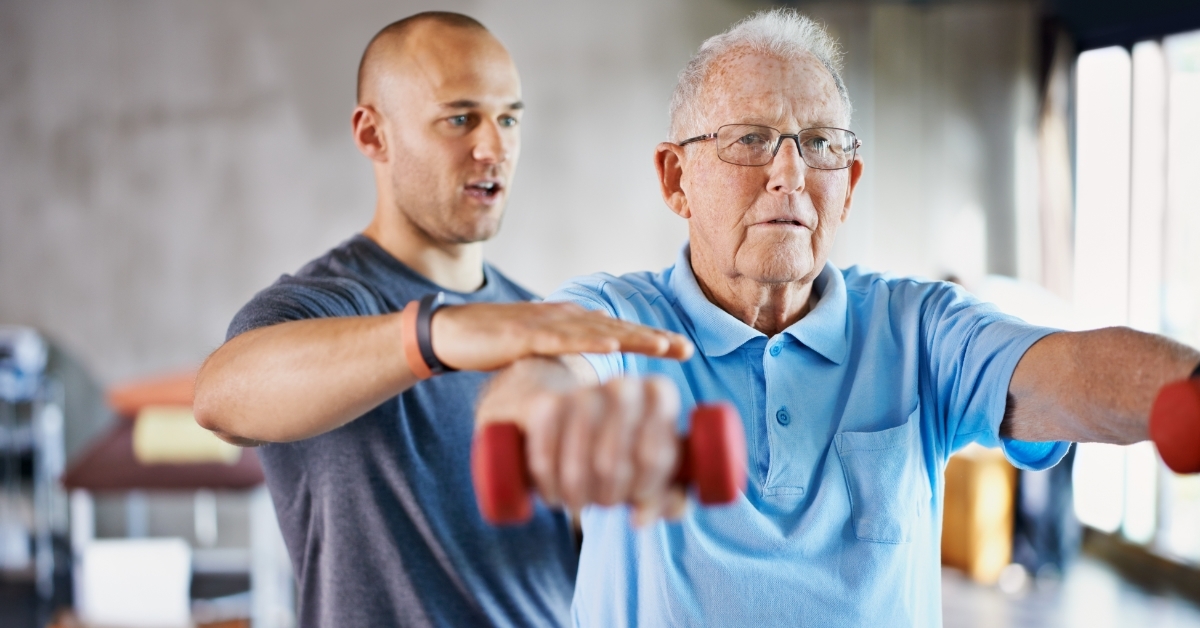 physiotherapist helping senior man with weights