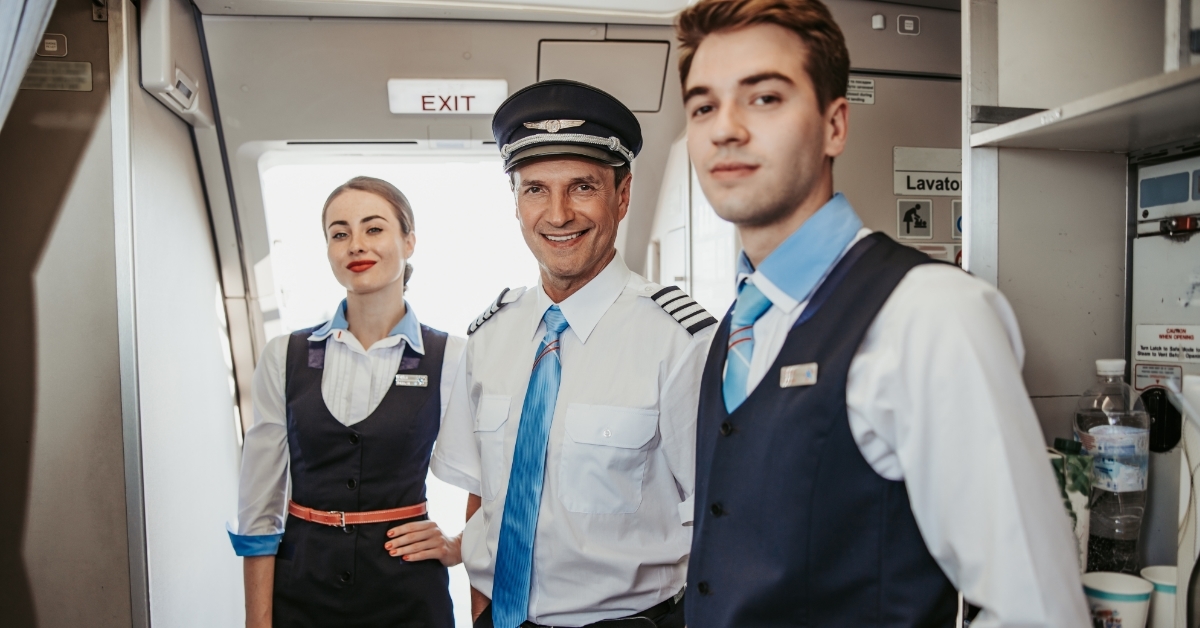 smiling pilot with attendants on airplane board