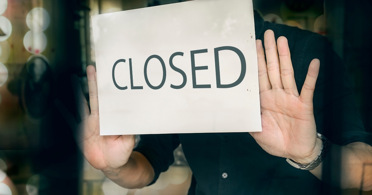 man putting closed sign 