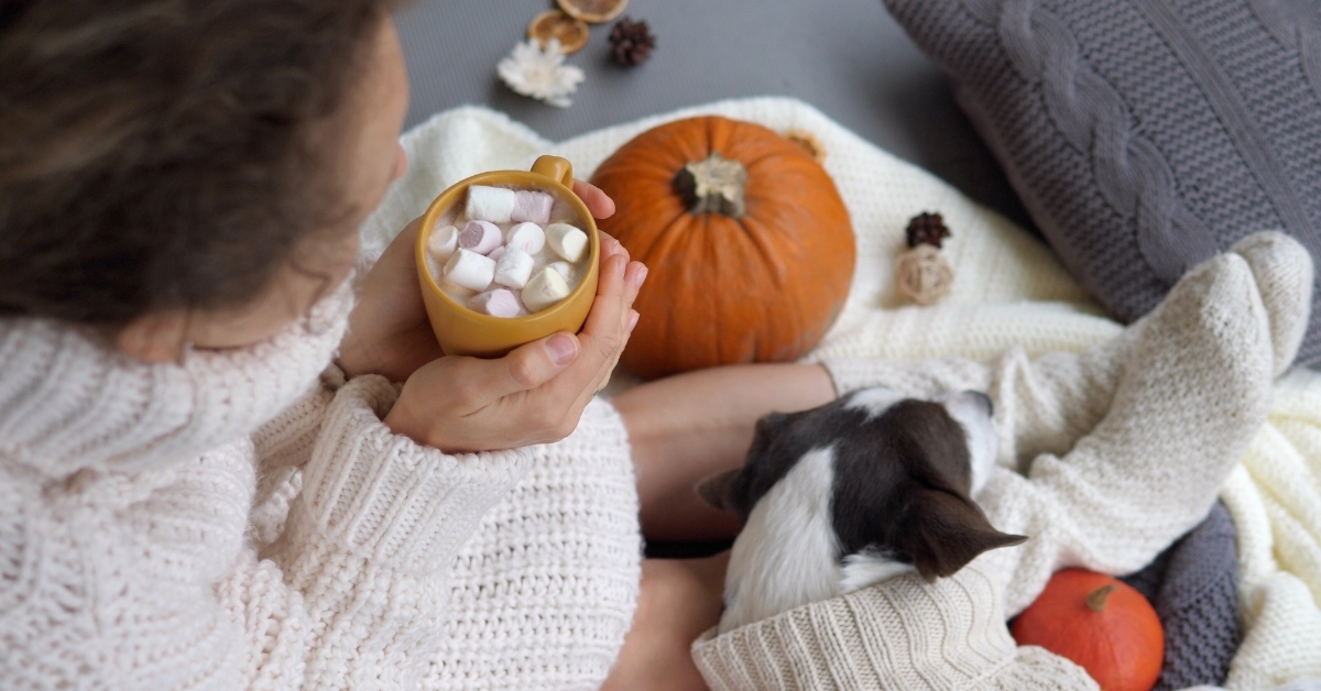 woman having hot cocoa with dog