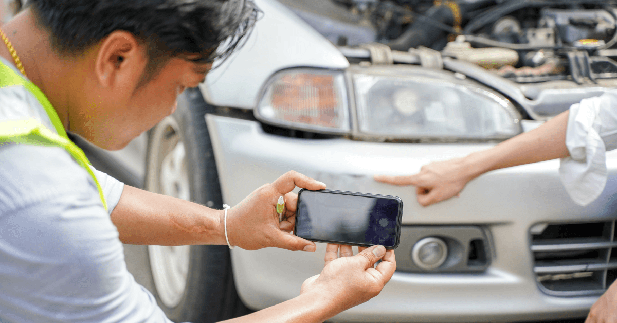 A man takes a picture of a car accident.