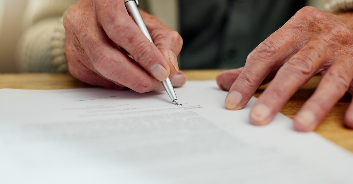 senior man signing away retirement papers