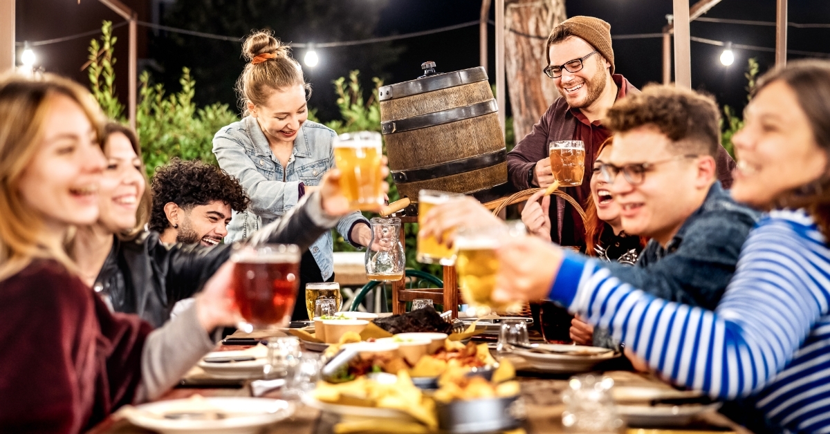 Young men and women having fun drinking out at beer garden patio