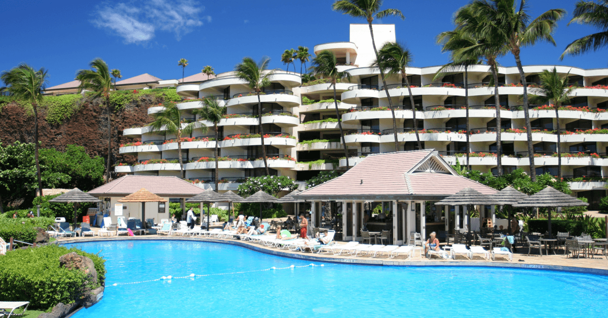 People lounging by pool at tropical resort