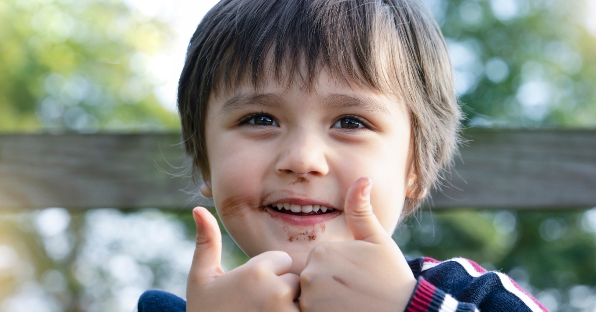 boy with dirty face doing thumbs up