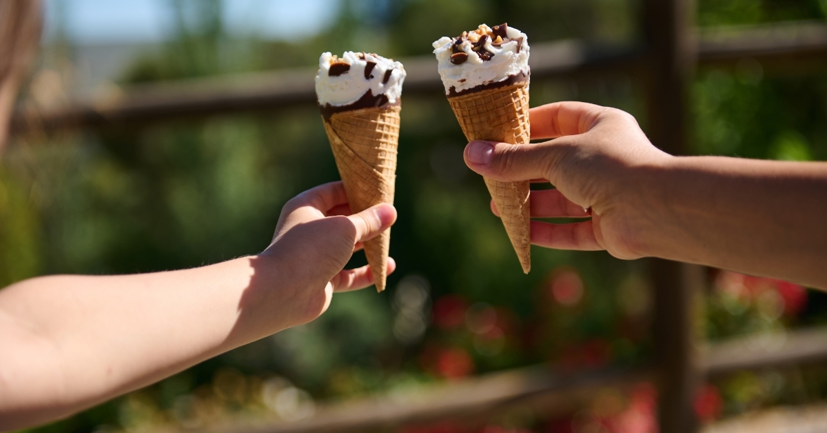 Two people holding ice cream cones outdoors
