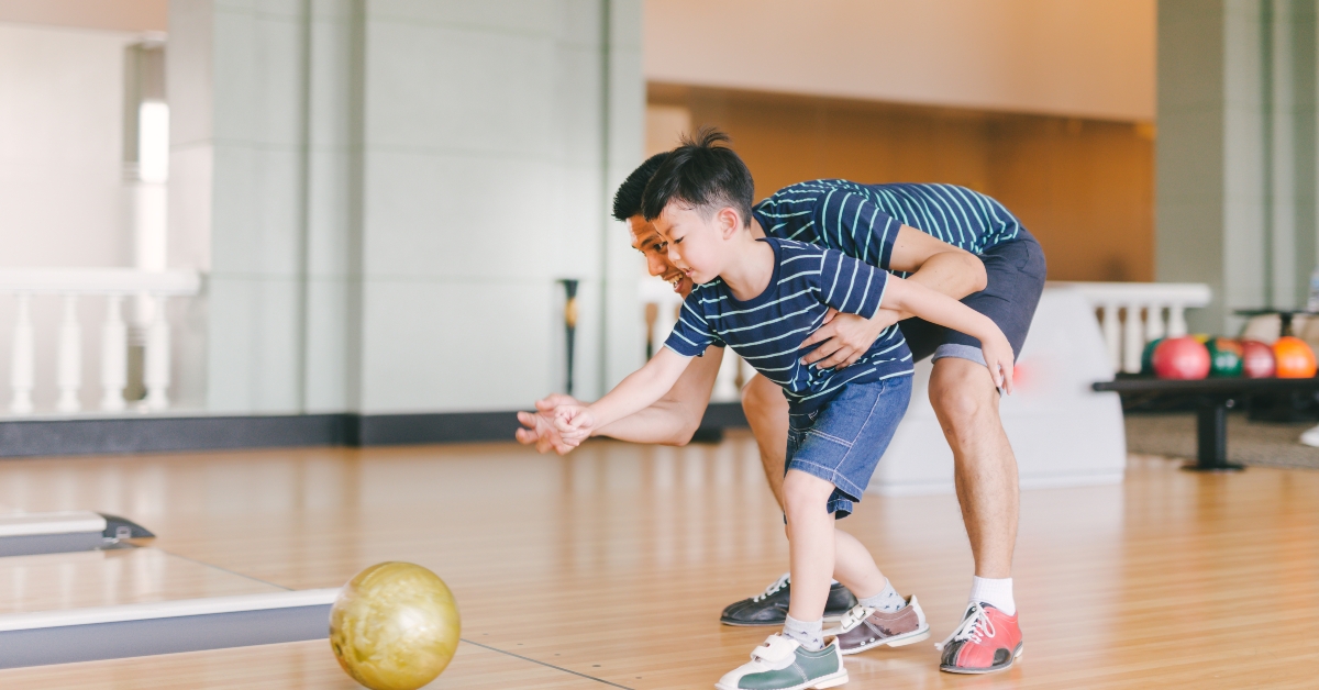 asian family having fun at bowling club