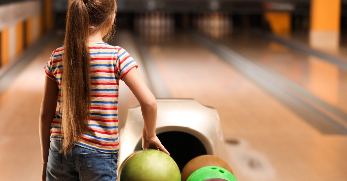 little girl near balls in bowling club