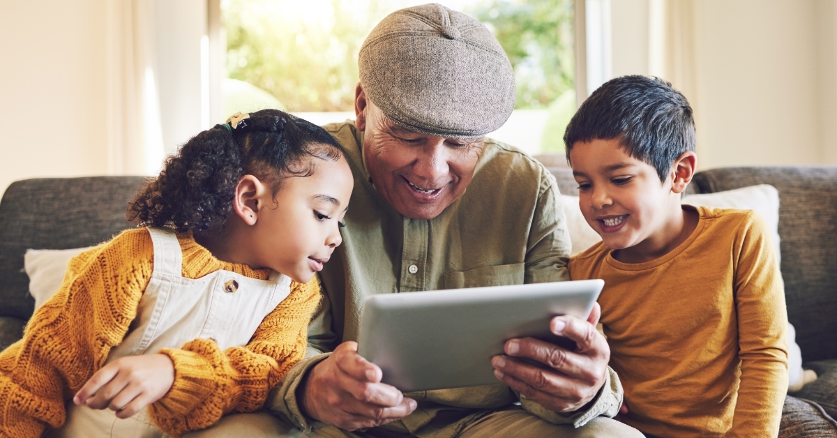 kids watching tablet with grandfather