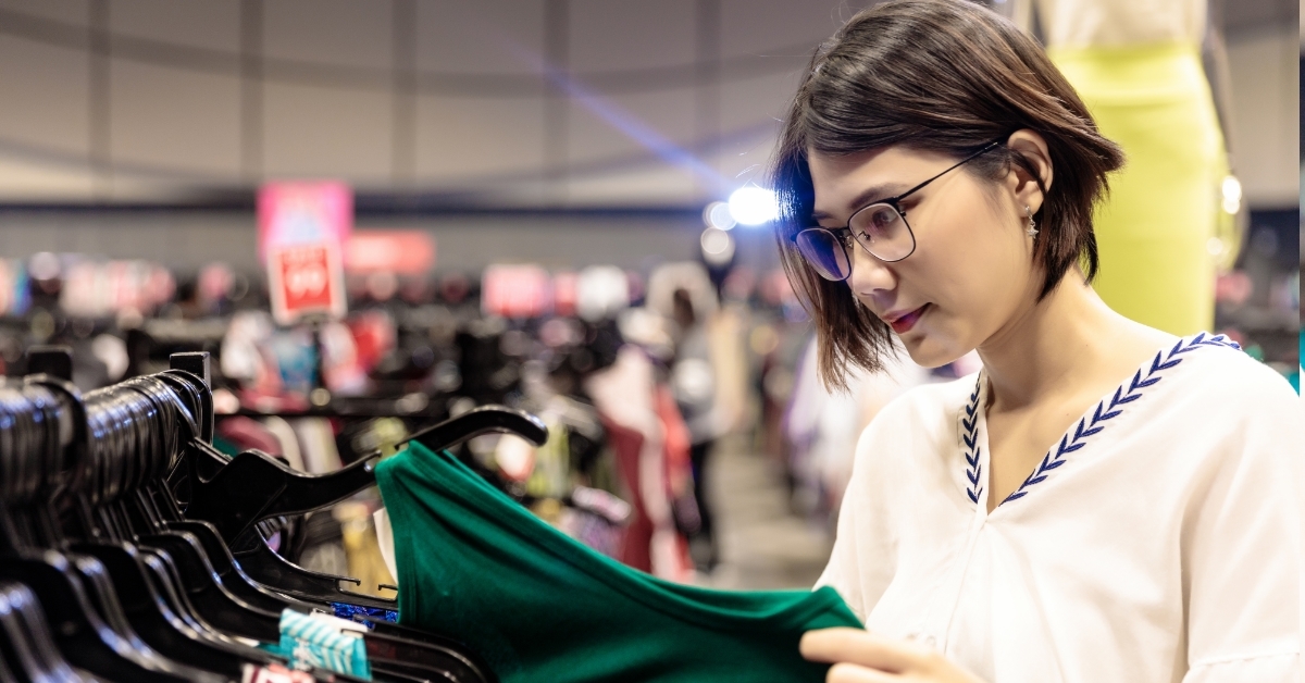 asian woman choosing shirts from rack