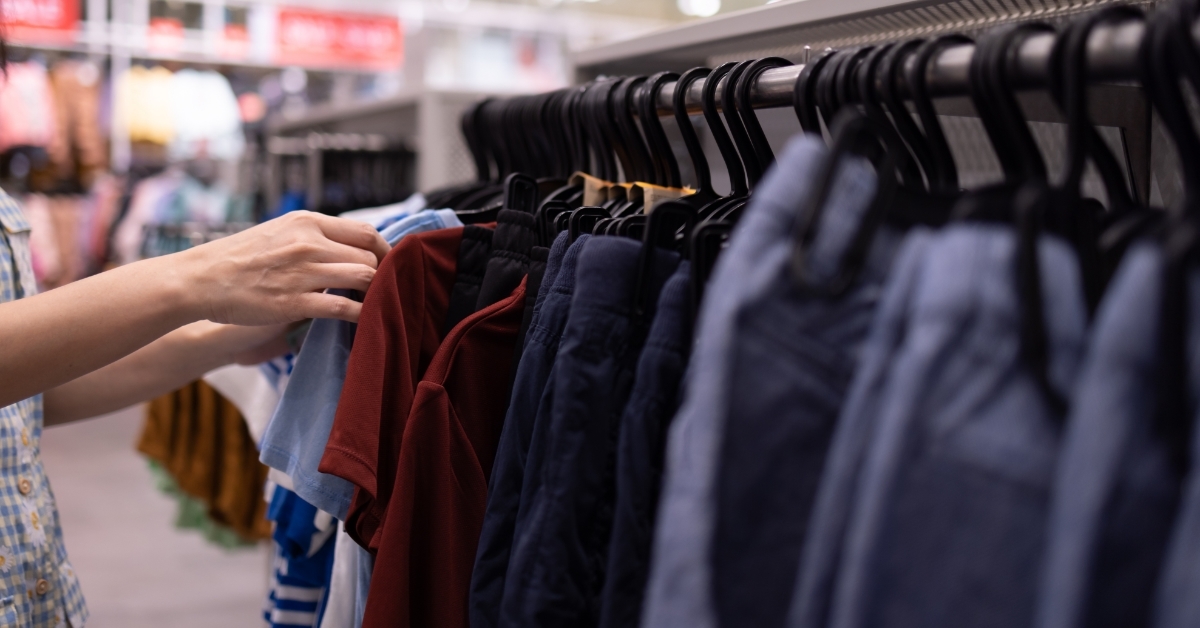 woman checking clothes on hangers at store